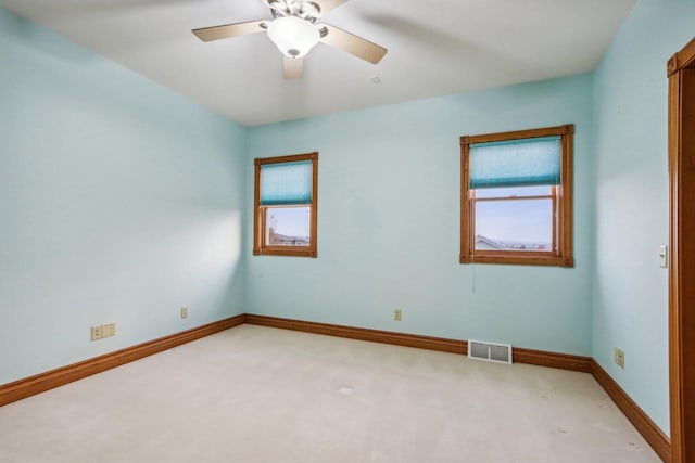 spare room featuring light carpet, ceiling fan, and a healthy amount of sunlight