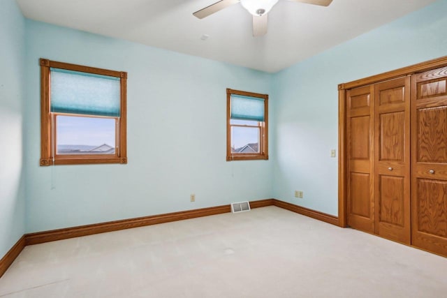 unfurnished bedroom with multiple windows, light carpet, and ceiling fan