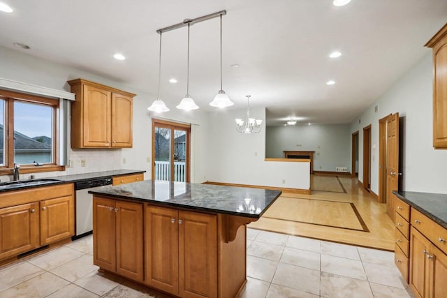 kitchen featuring sink, a center island, stainless steel dishwasher, dark stone counters, and pendant lighting