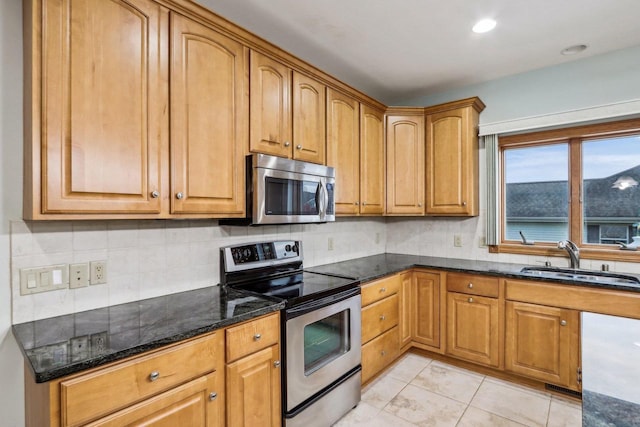 kitchen with sink, backsplash, dark stone countertops, light tile patterned floors, and appliances with stainless steel finishes