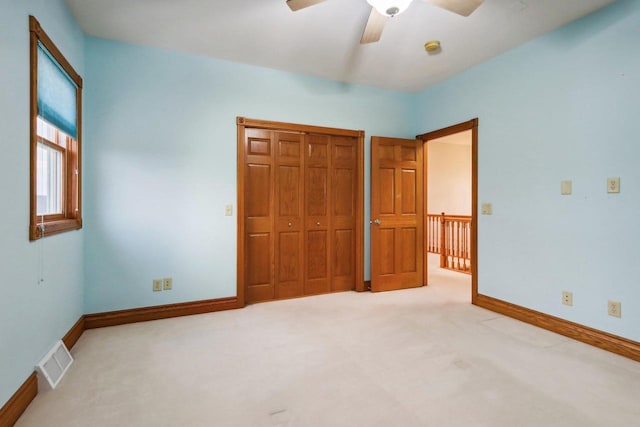 unfurnished bedroom featuring ceiling fan, light colored carpet, and a closet