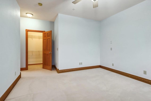 unfurnished bedroom featuring ceiling fan, a closet, light colored carpet, and a spacious closet