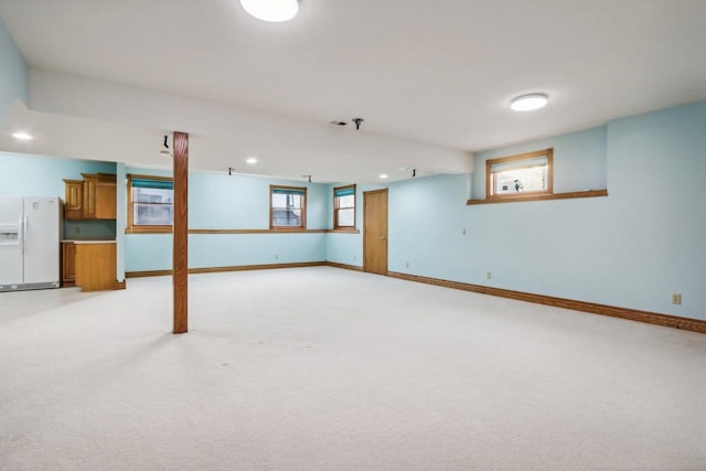 basement featuring light colored carpet and white fridge with ice dispenser