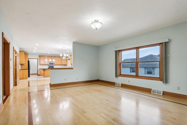 unfurnished living room with light hardwood / wood-style floors and an inviting chandelier