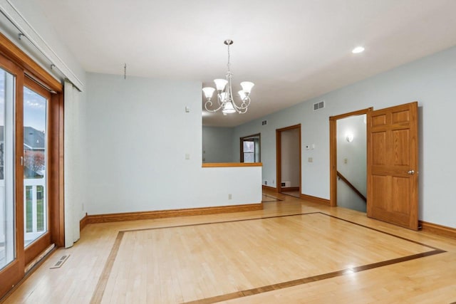 spare room with a wealth of natural light, hardwood / wood-style floors, and a notable chandelier