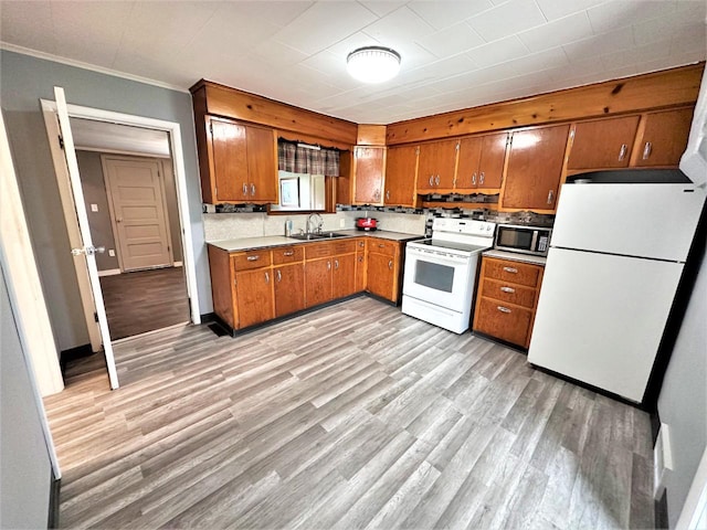 kitchen featuring ornamental molding, light wood-type flooring, white appliances, and sink