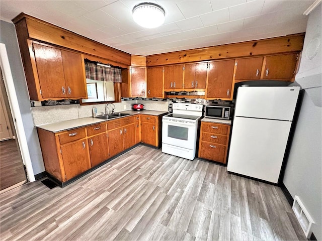 kitchen with light hardwood / wood-style flooring, white appliances, backsplash, and sink