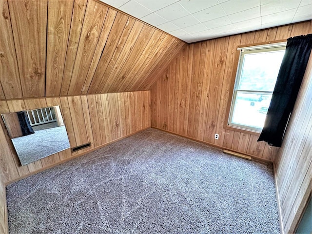 additional living space featuring wooden walls, vaulted ceiling, and dark colored carpet