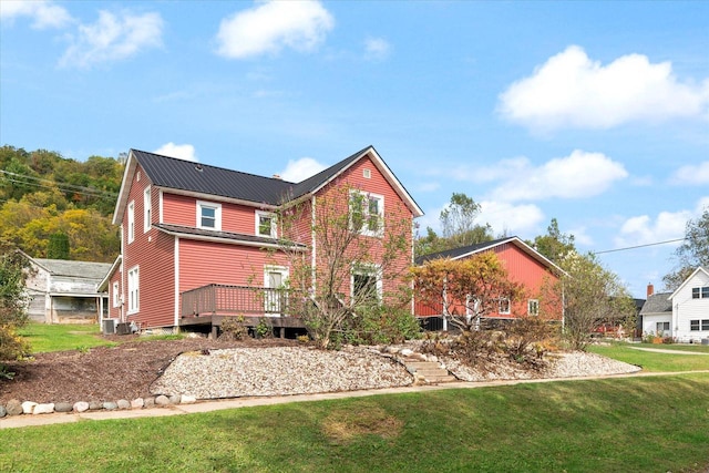 rear view of property featuring a wooden deck, central AC, and a yard