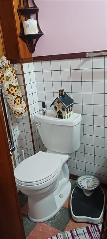 bathroom featuring toilet and tile walls