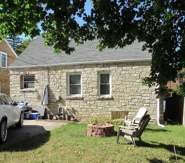 back of house featuring a fire pit and a yard