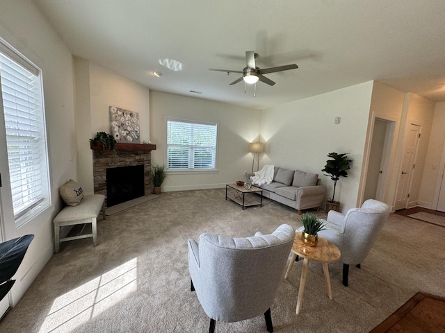 carpeted living room featuring ceiling fan and a stone fireplace