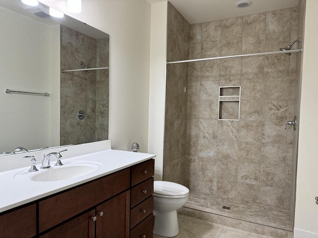 bathroom featuring a tile shower, tile patterned flooring, vanity, and toilet