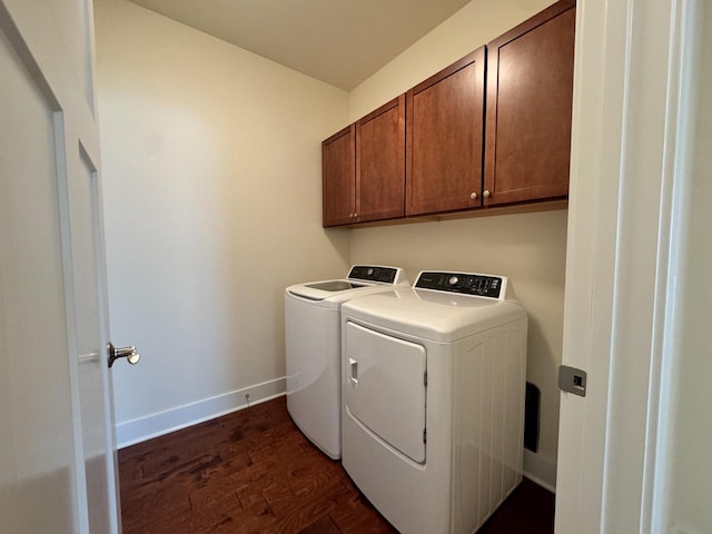 clothes washing area featuring washing machine and clothes dryer, cabinets, and dark hardwood / wood-style flooring