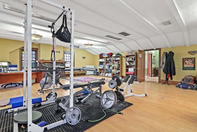 exercise area featuring a textured ceiling, lofted ceiling, and hardwood / wood-style floors