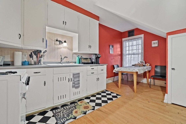 kitchen featuring white cabinets, sink, light hardwood / wood-style flooring, white stove, and vaulted ceiling