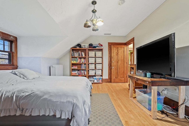 bedroom featuring an inviting chandelier, wood-type flooring, vaulted ceiling, and radiator