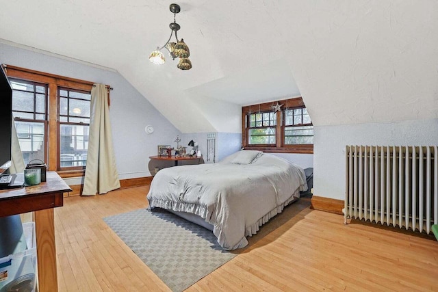 bedroom featuring radiator heating unit, light wood-type flooring, and vaulted ceiling