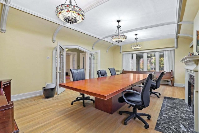 office area featuring light wood-type flooring, a fireplace, ornamental molding, and french doors