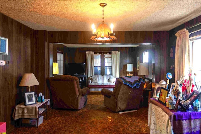 carpeted living room featuring a textured ceiling, wood walls, and a chandelier