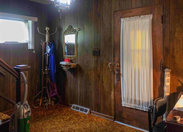 carpeted entryway featuring wood walls