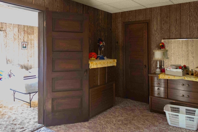 kitchen with a drop ceiling, wood walls, and carpet floors