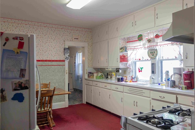 kitchen with dark carpet, white cabinets, sink, white appliances, and ventilation hood