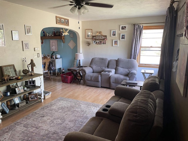 living room with a textured ceiling, wood-type flooring, and ceiling fan