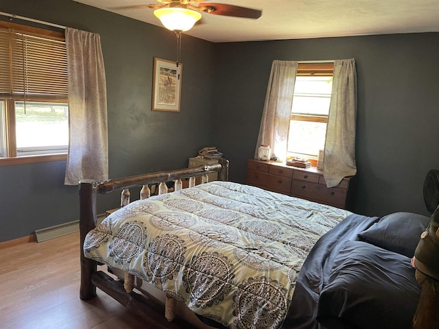 bedroom with a baseboard heating unit, hardwood / wood-style floors, and ceiling fan