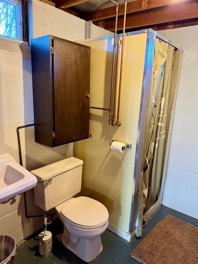 bathroom with concrete flooring, sink, curtained shower, and toilet