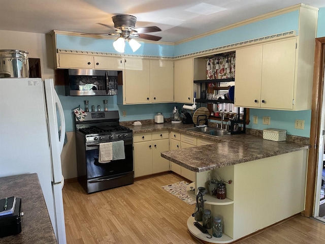 kitchen featuring cream cabinets, black range with gas stovetop, sink, and kitchen peninsula