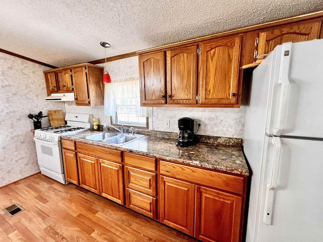 kitchen featuring light hardwood / wood-style floors, white appliances, a textured ceiling, crown molding, and sink