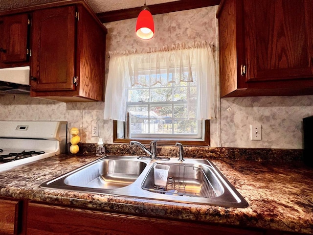 kitchen with pendant lighting, a textured ceiling, sink, and range hood