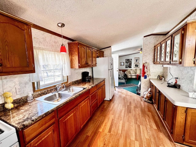 kitchen with pendant lighting, white refrigerator, light hardwood / wood-style floors, a textured ceiling, and sink