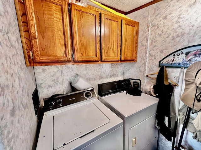 laundry area with a textured ceiling, crown molding, separate washer and dryer, and cabinets