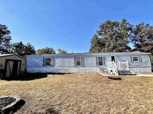 manufactured / mobile home with a front yard, a fire pit, a storage shed, and a patio area