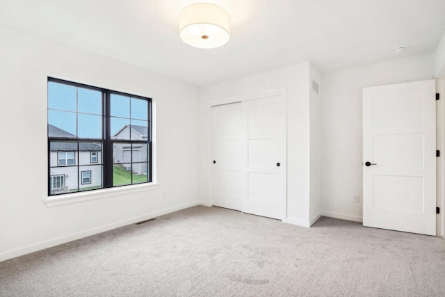 unfurnished bedroom with light carpet and a closet