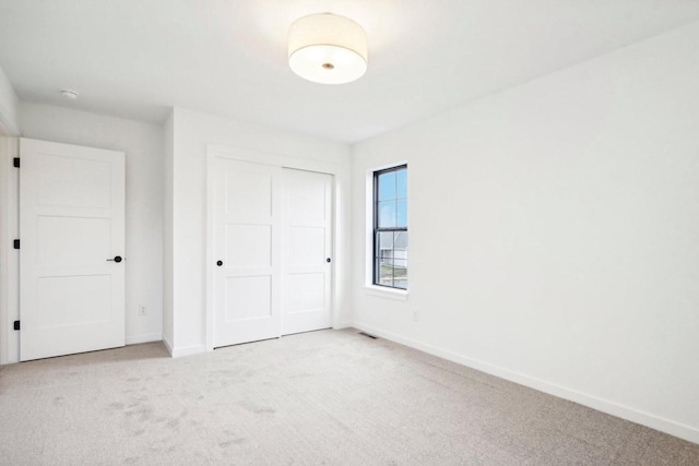 unfurnished bedroom with light colored carpet and a closet