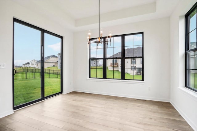 unfurnished dining area with a wealth of natural light, light hardwood / wood-style floors, and a notable chandelier