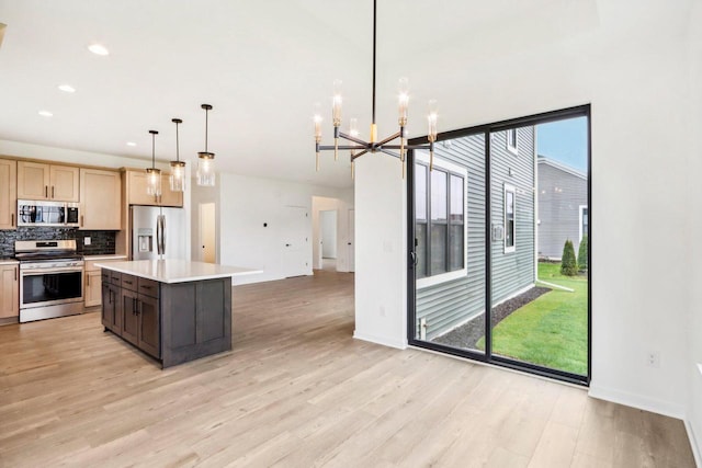 kitchen featuring backsplash, hanging light fixtures, light hardwood / wood-style floors, appliances with stainless steel finishes, and a kitchen island