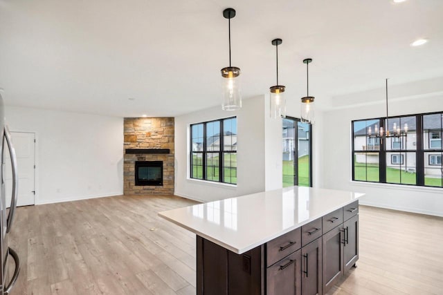 kitchen with decorative light fixtures, light wood-type flooring, and a fireplace