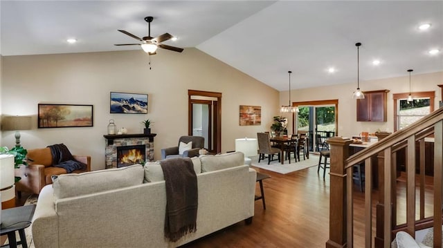 living room with ceiling fan, a stone fireplace, dark hardwood / wood-style floors, and vaulted ceiling