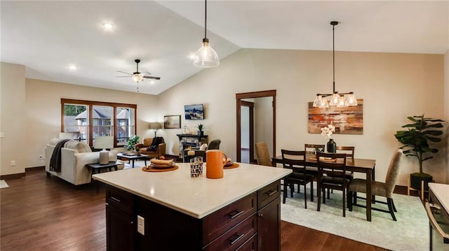 kitchen with a center island, dark wood-type flooring, ceiling fan with notable chandelier, hanging light fixtures, and vaulted ceiling