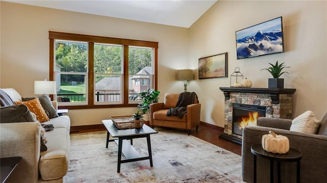 sitting room featuring a stone fireplace, hardwood / wood-style flooring, and vaulted ceiling