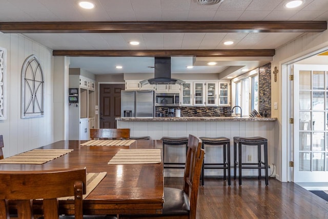 dining space with wooden walls, sink, and dark wood-type flooring