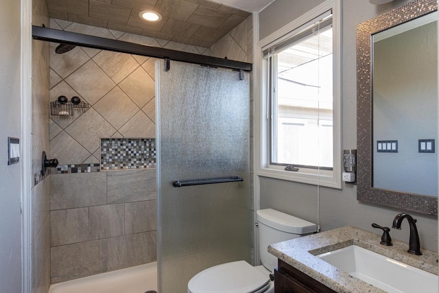 bathroom with a shower with shower door, vanity, and toilet