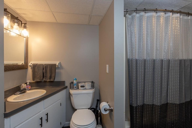 full bathroom featuring a drop ceiling, shower / tub combo with curtain, vanity, and toilet