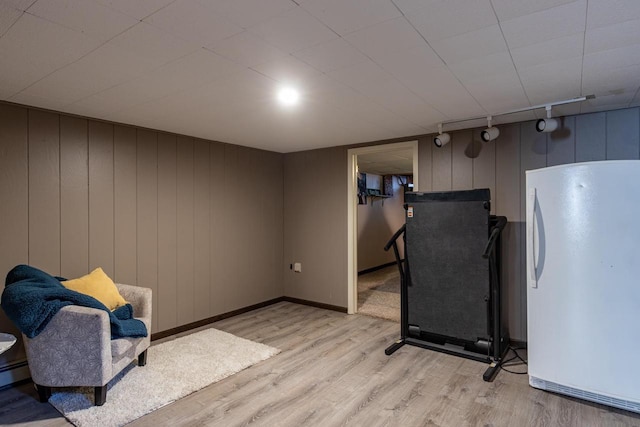 sitting room with light hardwood / wood-style flooring, wooden walls, and track lighting