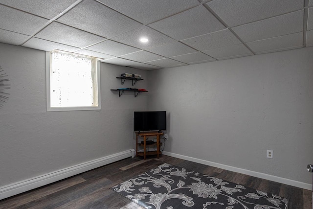 unfurnished room featuring a paneled ceiling, a baseboard heating unit, and dark wood-type flooring