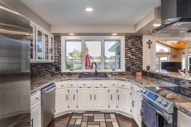 kitchen with appliances with stainless steel finishes, white cabinetry, sink, and wall chimney range hood